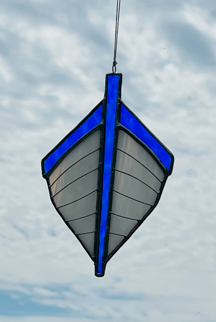 Our traditional punt-shaped stained glass suncatcher is white with a blue trim. Hung with a blue sky background.