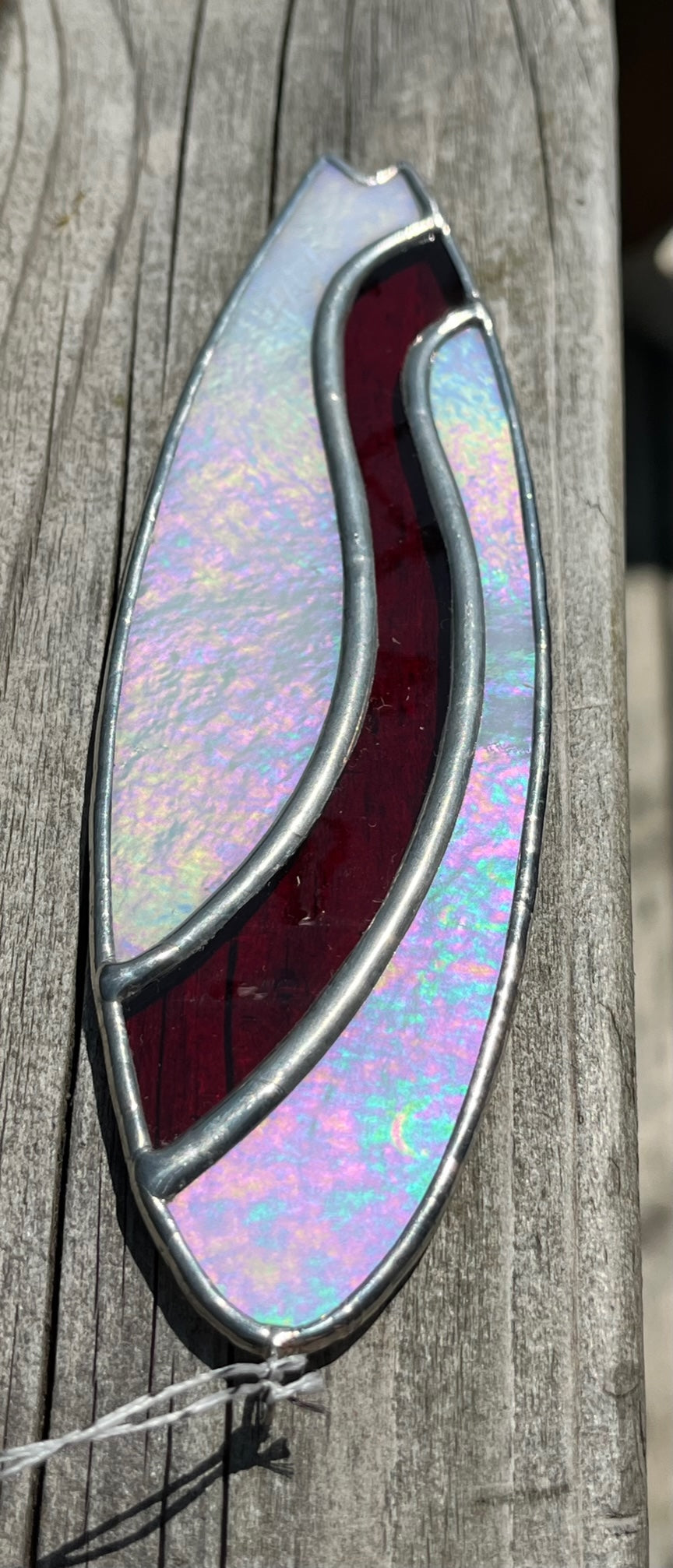 A stained glass shortboard that is made with white opalescent glass with a red glass wave down the center. 