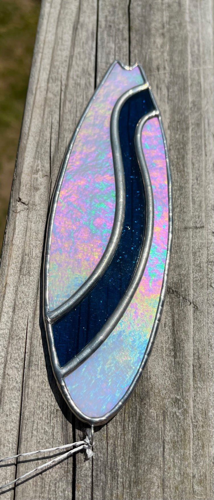 A stained glass shortboard that is made with white opalescent glass with a blue glass wave down the center. 